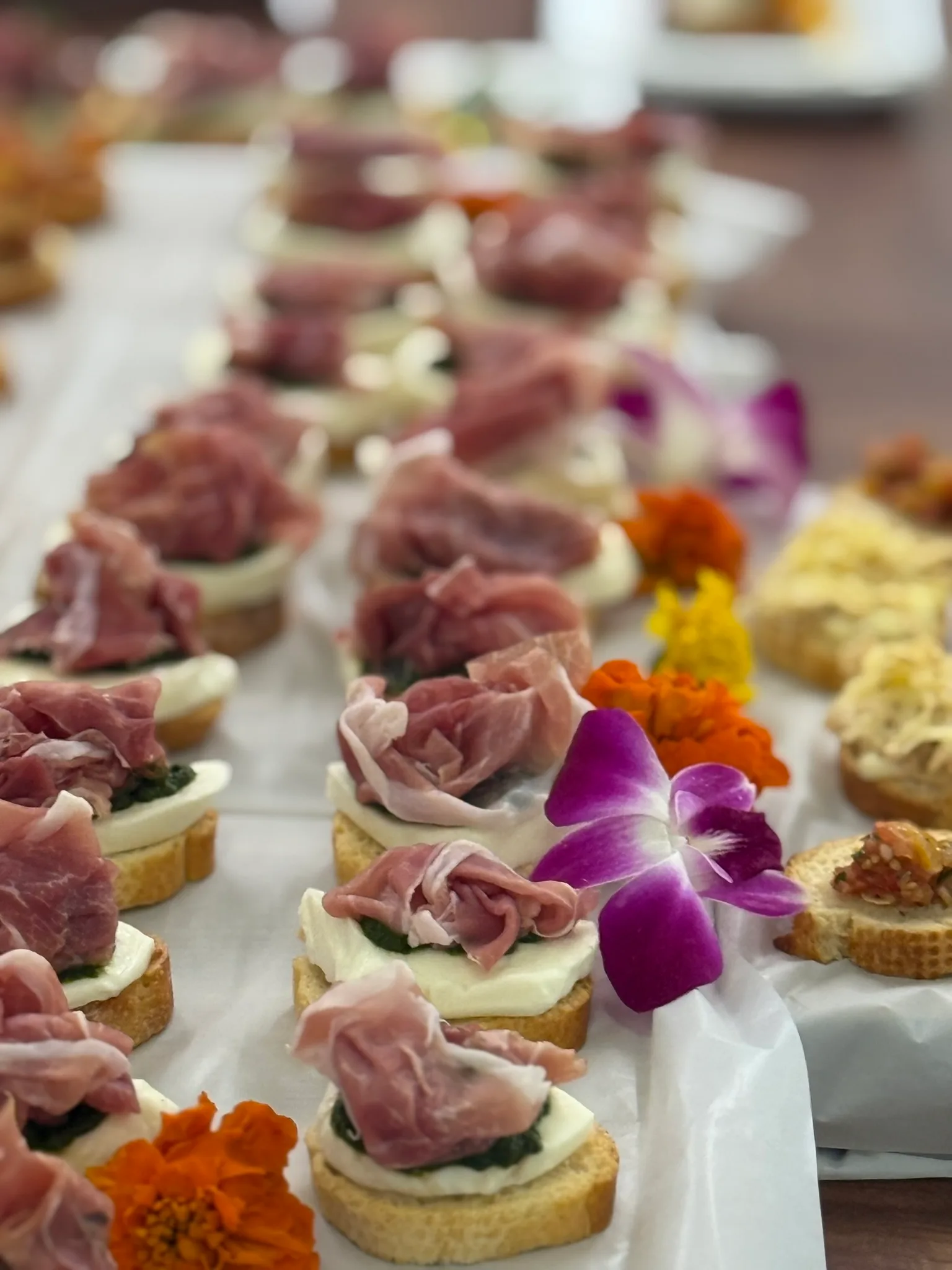 Prosciutto and mozzarella crostini with edible orchids by Chef Matija