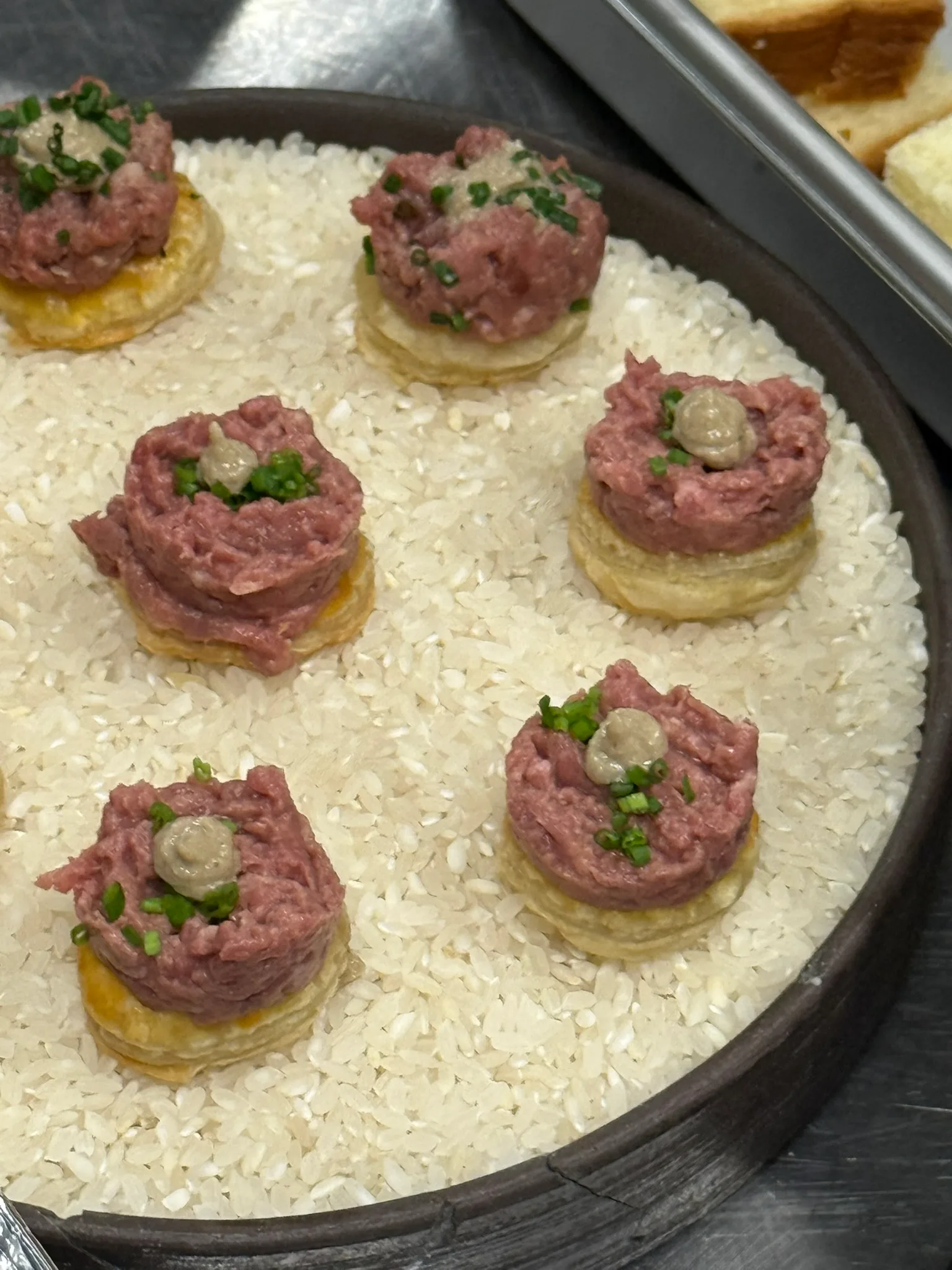 Beef tartare on puff pastry rounds presented on a bed of rice