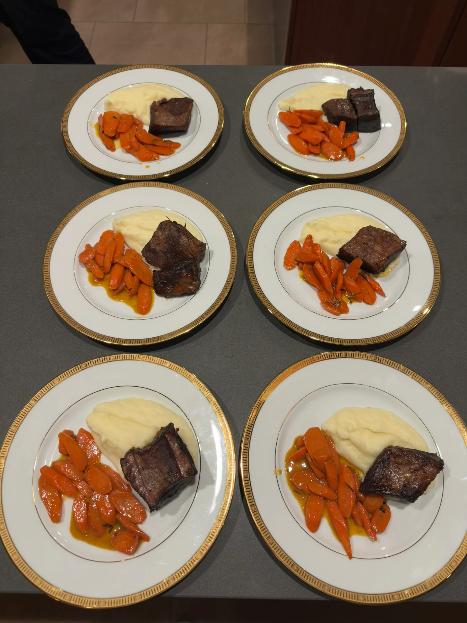 Braised short ribs with mashed potatoes and glazed carrots on gold-rimmed plates