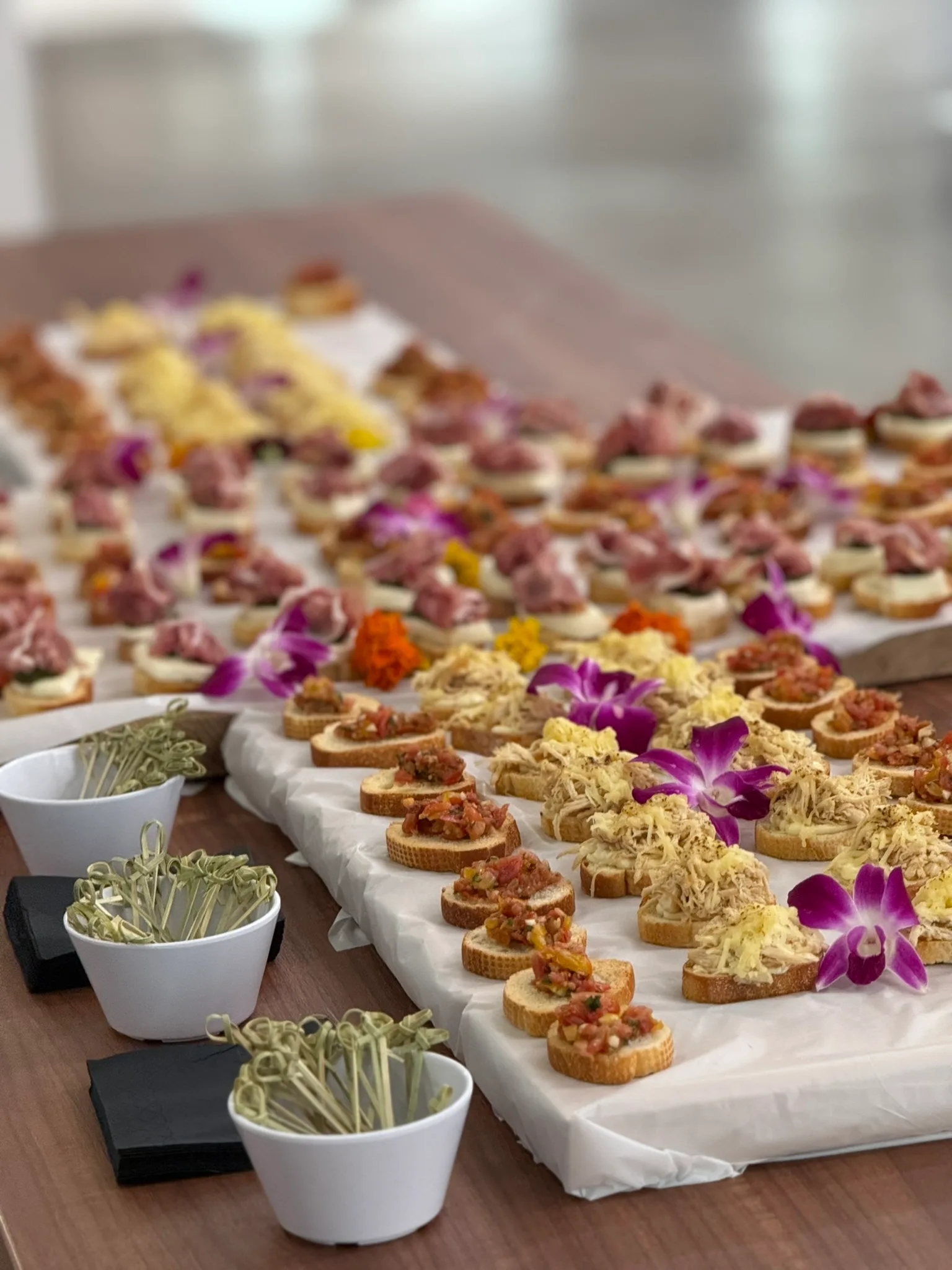 Full catering display with assorted crostini, orchids, and toothpick garnishes