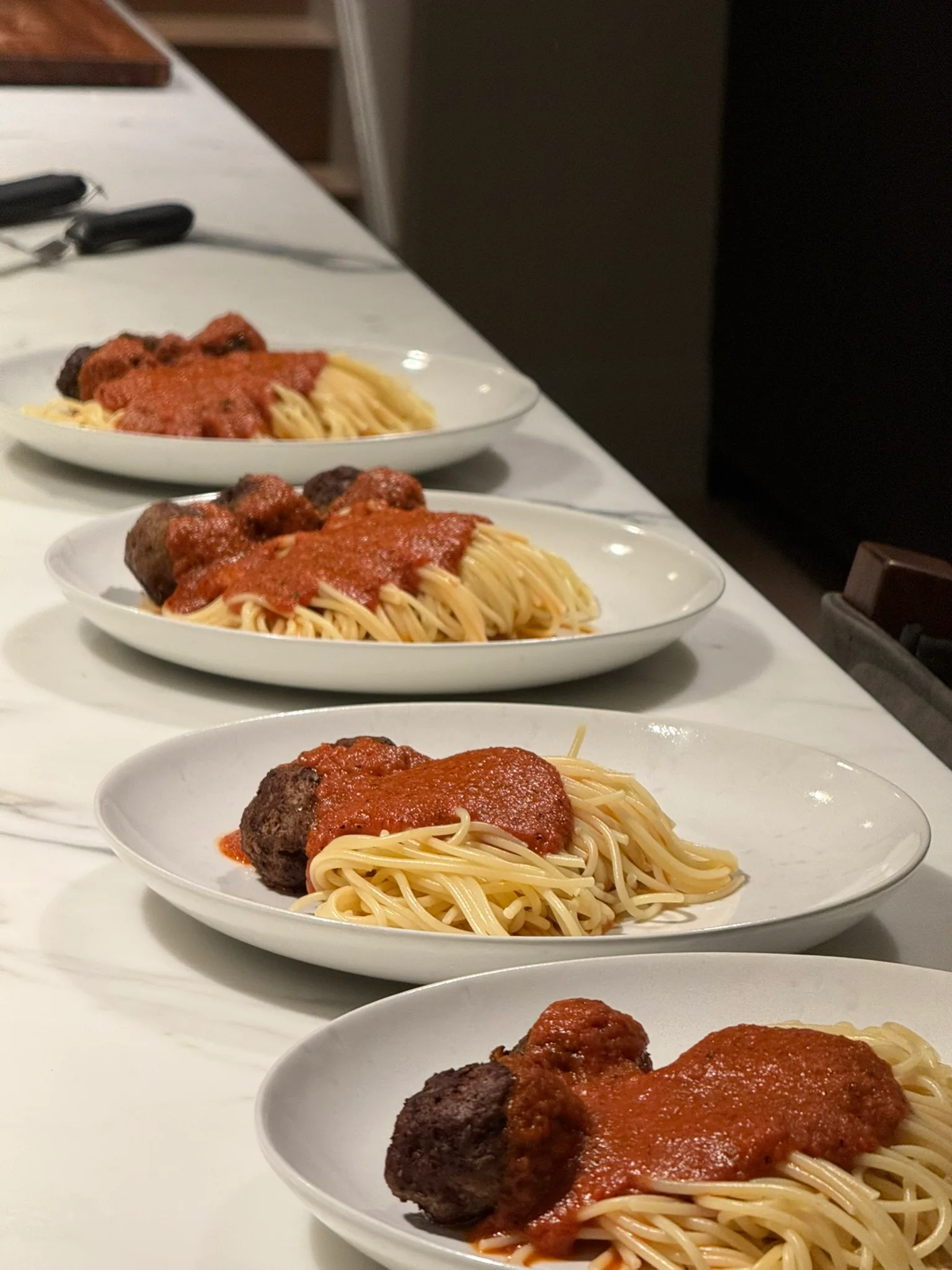 Spaghetti and meatballs with marinara sauce plated in a row