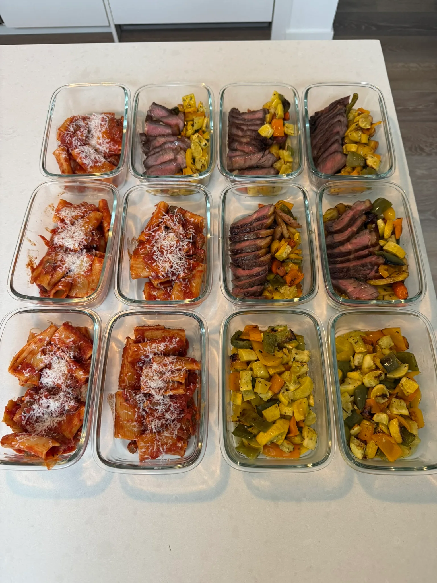 Meal prep containers with rigatoni, sliced steak, and roasted vegetables